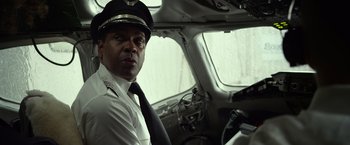 Movie still from “Flight” (2012), directed by Robert Zemeckis – A man in a pilot's uniform sitting in the cockpit of an airplane; Medium shot, Low angle