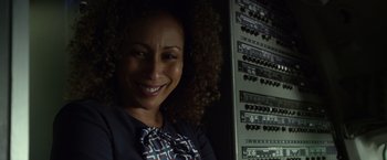 Movie still from “Flight” (2012), directed by Robert Zemeckis – A woman smiling in front of a bunch of computer equipment; Close Up shot, Low angle