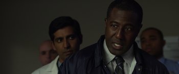 Movie still from “Flight” (2012), directed by Robert Zemeckis – A man in a suit and tie standing next to another man; Close Up shot, Over the shoulder angle