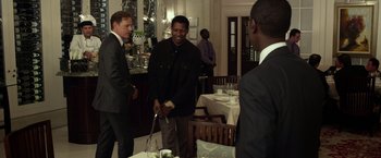 Movie still from “Flight” (2012), directed by Robert Zemeckis – A group of men standing around a table in a restaurant; Medium shot, Over the shoulder angle