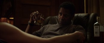 Movie still from “Flight” (2012), directed by Robert Zemeckis – A man sitting in a chair holding a glass of whiskey; Medium shot, Low angle