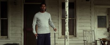Movie still from “Flight” (2012), directed by Robert Zemeckis – A man standing in front of a house holding a cane; Medium shot, Low angle