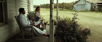 Movie still from “Flight” (2012), directed by Robert Zemeckis – Two people sitting on a porch reading a book; Wide shot, Low angle