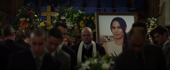 Movie still from “Flight” (2012), directed by Robert Zemeckis – A group of people gathered around a portrait of a woman in front of flowers; Close Up shot, Over the shoulder angle