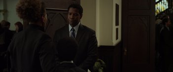 Movie still from “Flight” (2012), directed by Robert Zemeckis – A man wearing a suit and tie sitting in front of another man in a suit; Medium shot, Over the shoulder angle