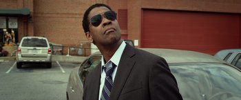 Movie still from “Flight” (2012), directed by Robert Zemeckis – A man in a suit and sunglasses standing in front of a car; Close Up shot, Low angle