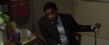 Movie still from “Flight” (2012), directed by Robert Zemeckis – A man in a suit and tie sitting in a chair; Close Up shot, High angle