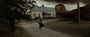 Movie still from “Flight” (2012), directed by Robert Zemeckis – A woman walking down a dirt road holding a suitcase; Extreme Wide shot, Low angle
