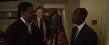 Movie still from “Flight” (2012), directed by Robert Zemeckis – A group of men in suits and ties standing in a hallway; Medium shot, Over the shoulder angle
