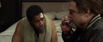 Movie still from “Flight” (2012), directed by Robert Zemeckis – A man smoking a cigarette while another man sits next to him; Medium shot, Over the shoulder angle