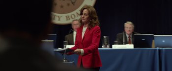Movie still from “Flight” (2012), directed by Robert Zemeckis – A woman in a red jacket stands in front of a microphone; Medium shot, Over the shoulder angle