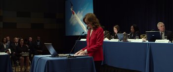 Movie still from “Flight” (2012), directed by Robert Zemeckis – A woman in a red jacket using a laptop; Medium shot, Low angle