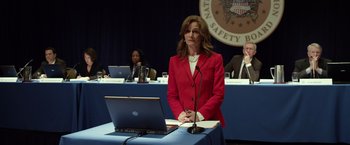 Movie still from “Flight” (2012), directed by Robert Zemeckis – A woman standing at a podium in front of a computer; Medium shot, Over the shoulder angle