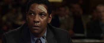 Movie still from “Flight” (2012), directed by Robert Zemeckis – A man in a suit with a bandage on his head; Close Up shot, Over the shoulder angle