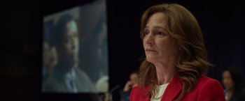 Movie still from “Flight” (2012), directed by Robert Zemeckis – A woman in a red jacket is looking at a tv screen; Close Up shot, Over the shoulder angle