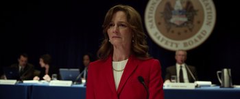Movie still from “Flight” (2012), directed by Robert Zemeckis – A woman in a red jacket is standing in front of a microphone; Close Up shot, Over the shoulder angle