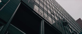 Movie still from “Flight/Risk” (2022), directed by Karim Amer – A tall building with a lot of windows on the side of it; Extreme Wide shot, Low angle