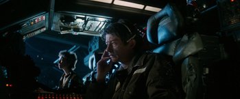Movie still from “Alien” (1979), directed by Ridley Scott – A man sitting in a chair talking on a cell phone; Medium shot, Low angle