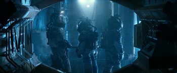 Movie still from “Alien” (1979), directed by Ridley Scott – A group of people in space suits standing in a room; Wide shot, Low angle
