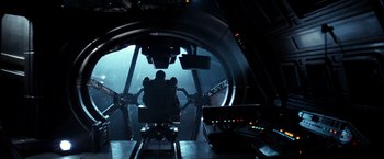 Movie still from “Alien” (1979), directed by Ridley Scott – A man sitting in a chair inside of an airplane; Wide shot, High angle