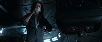 Movie still from “Alien” (1979), directed by Ridley Scott – A woman drinking a cup of coffee in a dark room; Medium shot, Low angle