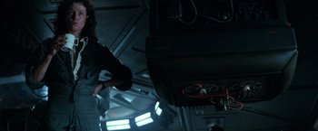 Movie still from “Alien” (1979), directed by Ridley Scott – A person standing in a dark room with wires hanging from the ceiling; Medium shot, Low angle