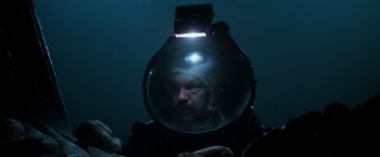 Movie still from “Alien” (1979), directed by Ridley Scott – A man with a helmet on his head in the dark; Close Up shot, Overhead angle