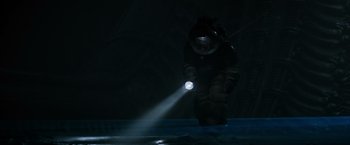 Movie still from “Alien” (1979), directed by Ridley Scott – A man in a black suit is holding a flashlight; Wide shot, Low angle
