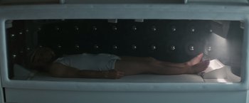Movie still from “Alien” (1979), directed by Ridley Scott – A man laying on a bed in front of a wall; Medium shot, Overhead angle