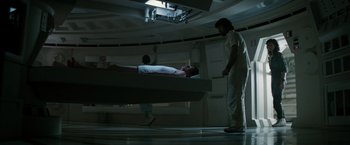 Movie still from “Alien” (1979), directed by Ridley Scott – A man standing next to a bed in a dark room; Wide shot, Low angle