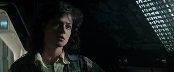 Movie still from “Alien” (1979), directed by Ridley Scott – A woman in a uniform is standing in a dark room; Close Up shot, Low angle