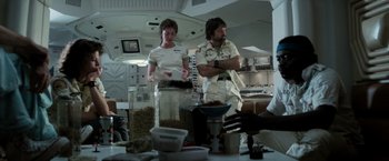 Movie still from “Alien” (1979), directed by Ridley Scott – A couple of people standing in a room with food; Medium shot, Low angle
