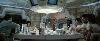 Movie still from “Alien” (1979), directed by Ridley Scott – A group of people sitting at a table in a room; Medium shot, Low angle