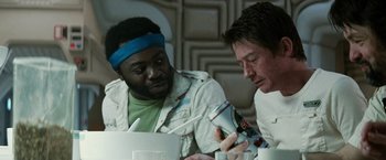 Movie still from “Alien” (1979), directed by Ridley Scott – Two men are sitting at a table and one of the men is holding a can of beer; Close Up shot, Over the shoulder angle