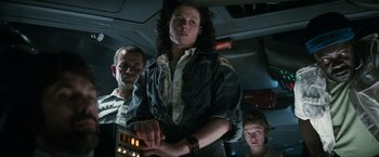 Movie still from “Alien” (1979), directed by Ridley Scott – A group of people standing next to each other in a room; Medium shot, Low angle