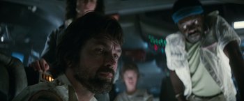 Movie still from “Alien” (1979), directed by Ridley Scott – A group of people standing around a man with a beard; Close Up shot, Low angle