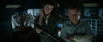 Movie still from “Alien” (1979), directed by Ridley Scott – A woman standing next to a man holding a sword; Medium shot, Low angle