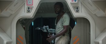 Movie still from “Alien” (1979), directed by Ridley Scott – A man standing in a room holding a gun; Medium shot, Low angle