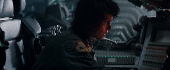 Movie still from “Alien” (1979), directed by Ridley Scott – A man in a green jacket is sitting in front of a computer keyboard; Close Up shot, Low angle