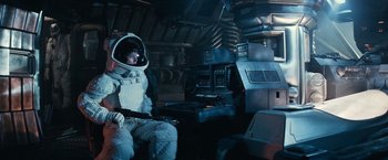 Movie still from “Alien” (1979), directed by Ridley Scott – A man in a spacesuit sitting in a room; Wide shot, High angle