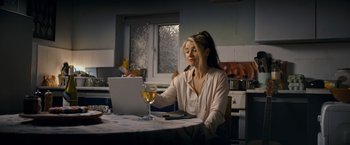 Movie still from “Flora and Son” (2023), directed by John Carney – A woman sitting in front of a laptop computer; Medium shot, Over the shoulder angle