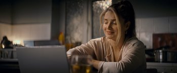 Movie still from “Flora and Son” (2023), directed by John Carney – A woman sitting in front of a computer at a table; Close Up shot, Over the shoulder angle