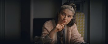 Movie still from “Flora and Son” (2023), directed by John Carney – A woman sitting in front of a wine glass; Close Up shot, Over the shoulder angle