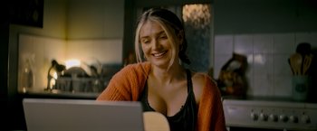 Movie still from “Flora and Son” (2023), directed by John Carney – A beautiful young lady sitting in front of an open laptop computer; Close Up shot, Over the shoulder angle