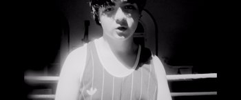 Movie still from “Flora and Son” (2023), directed by John Carney – A black and white photo of a person with a leaf on their shirt; Medium shot, High angle