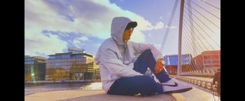 Movie still from “Flora and Son” (2023), directed by John Carney – A man sitting on the ground with a skateboard; Medium shot, Low angle