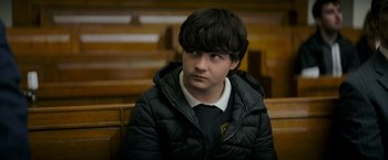 Movie still from “Flora and Son” (2023), directed by John Carney – A young man sitting in a bench wearing a black jacket; Close Up shot, High angle
