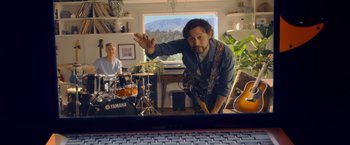 Movie still from “Flora and Son” (2023), directed by John Carney – A man standing in front of a mirror playing a guitar; Medium shot, Over the shoulder angle