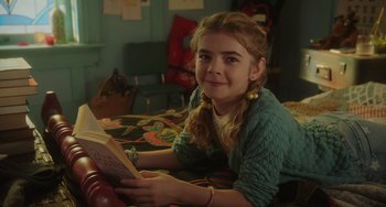 Movie still from “Flora & Ulysses” (2021), directed by Lena Khan – A young girl reading a book on a bed; Close Up shot, Over the shoulder angle