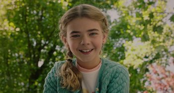 Movie still from “Flora & Ulysses” (2021), directed by Lena Khan – A young girl with long blonde hair in a green sweater; Close Up shot, High angle